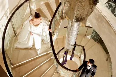 a bride and groom walking down a spiral staircase at The St. Regis Bangkok in Bangkok