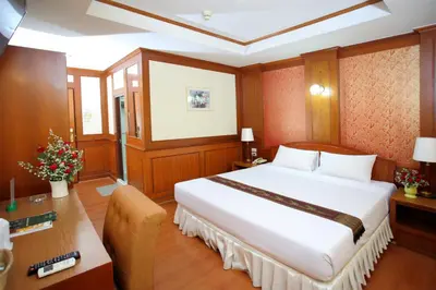 a bedroom with a large white bed and a desk at PJ Watergate Hotel in Bangkok