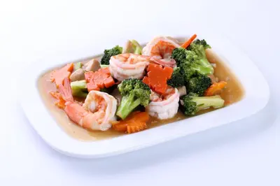a white bowl of shrimp and broccoli with sauce at PJ Watergate Hotel in Bangkok