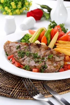a plate of meat and vegetables on a table at PJ Watergate Hotel in Bangkok