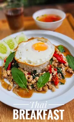 a plate of breakfast food with an egg on top at Phranakorn-Nornlen in Bangkok