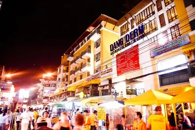a crowd of people walking down a street at night at Dang Derm Khaosan in Bangkok