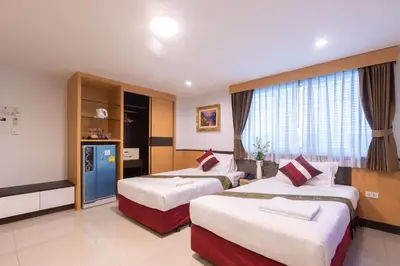 a hotel room with two beds and a television at Gusto Pratunam Hotel in Bangkok