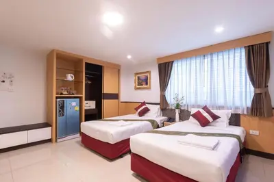 a hotel room with two beds and a television at Gusto Pratunam Hotel in Bangkok