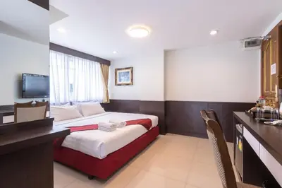 a bedroom with a bed and a desk and a television at Gusto Pratunam Hotel in Bangkok
