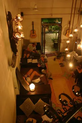two people sitting on a couch in a living room at Born Free Hostel in Bangkok