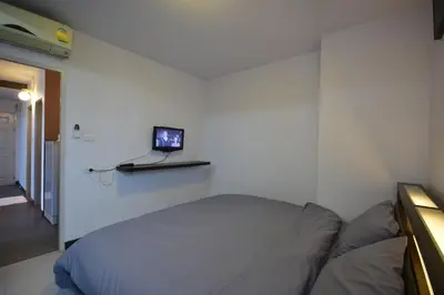 a bedroom with a bed and a laptop on a shelf at LOFT Salaya in Salaya