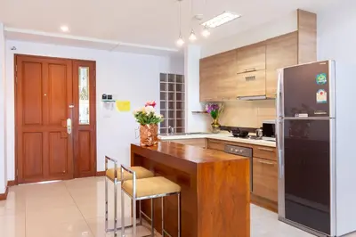 a kitchen with a wooden table and a black refrigerator at Lasalle Suites Hotel & Residence in Bangkok