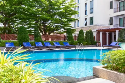 a swimming pool with blue lounge chairs and a building at Lasalle Suites Hotel & Residence in Bangkok