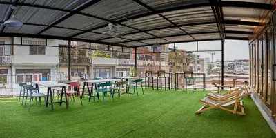 a room with tables and chairs and green grass at Timber Hostel in Bangkok