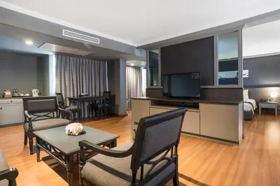 a living room with a television and a table and chairs at SC Park Hotel in Bangkok