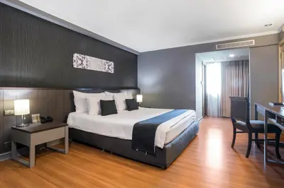 a hotel room with a bed and a table and chairs at SC Park Hotel in Bangkok