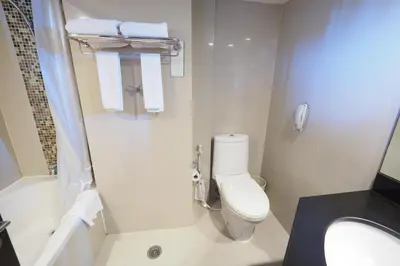 a bathroom with a toilet and a shower with towels at SC Park Hotel in Bangkok