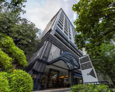 a tall building with a street sign in front of it at Cape House Hotel, Bangkok in Bangkok