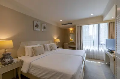 a hotel room with a large bed and a television at Cape House Hotel, Bangkok in Bangkok