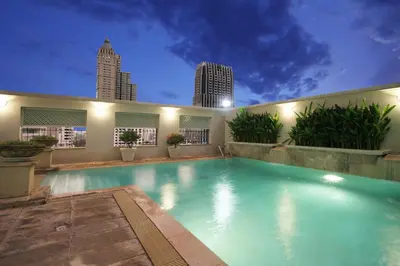 a large swimming pool with a city skyline in the background at Cape House Hotel, Bangkok in Bangkok