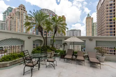 a patio with a table and chairs and buildings at Cape House Hotel, Bangkok in Bangkok