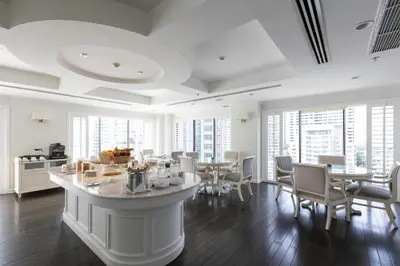 a white room with tables and chairs and windows at Cape House Hotel, Bangkok in Bangkok