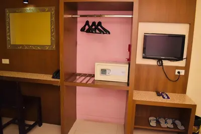 a room with a tv and a shelf with hangers at Royal Express Inn in Bangkok