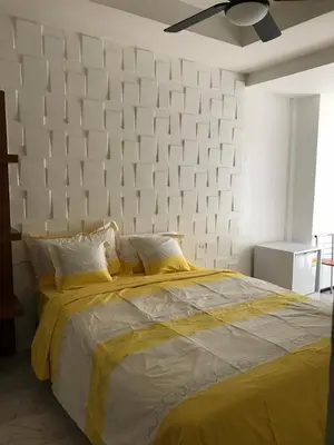 a bedroom with a large bed with a white wall at Nineplace 46 in Bangkok