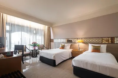 a hotel room with two beds and a table at Indra Regent Hotel in Bangkok