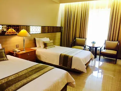 a hotel room with two beds and a table and chairs at Indra Regent Hotel in Bangkok