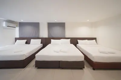 a room with two beds with white sheets at Grand Alpine Hotel in Bangkok