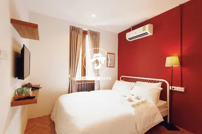 a bedroom with a white bed and a red wall at House Of PaPa Bangkok Siam in Bangkok