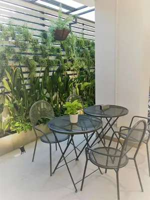 two tables and chairs in a room with plants at Bangkok Saran Poshtel in Bangkok