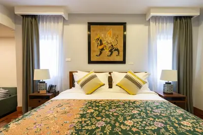 a bedroom with a large bed and two windows at Maneeya Park Residence in Bangkok