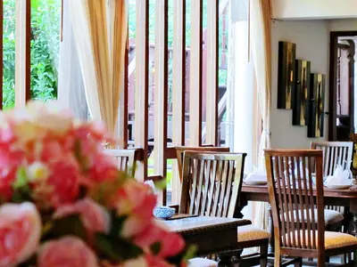 a dining room with a table and chairs and windows at Dhabkwan Resort in Nonthaburi