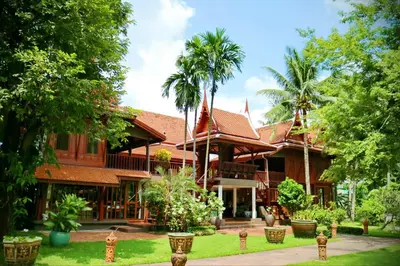 a house with palm trees in front of it at Dhabkwan Resort in Nonthaburi