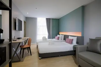 a hotel room with two beds and a desk at Hotel Tranz in Bangkok