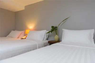 two white beds sitting next to each other in a room at Sabai Sathorn Service Apartment in Bangkok