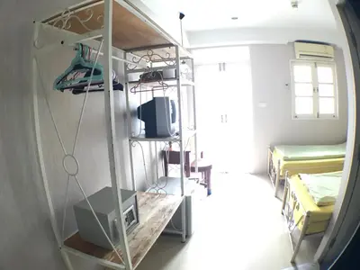 a room with a shelf with a tv and some beds at Roof View Place in Bangkok