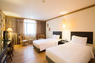 a hotel room with two beds and a television at The Tarntawan Hotel Surawong Bangkok in Bangkok