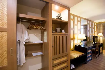 a room with a desk and a closet at The Tarntawan Hotel Surawong Bangkok in Bangkok