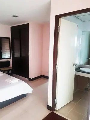 a bedroom with a bed and a bathroom with a mirror at Mok Mek 72 in Bangkok