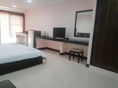a bedroom with a bed and a desk with a mirror at Mok Mek 72 in Bangkok