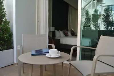 a table and chairs with a laptop and a coffee cup at The Rose Residence, Bangkok in Bangkok