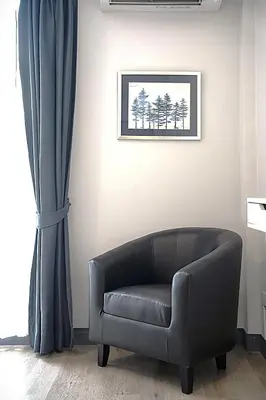 a black leather couch in a room with a window at Ratchadamnoen Residence in Bangkok