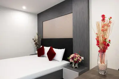 a bedroom with a bed with red pillows and a vase of flowers at DB Plus 5 in Bangkok