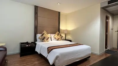 a bedroom with a large white bed with a large headboard at Fortuna Hotel in Bangkok