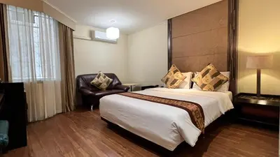 a hotel room with a large bed and a chair at Fortuna Hotel in Bangkok