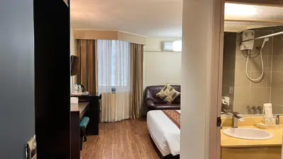 a hotel room with a bed and a sink at Fortuna Hotel in Bangkok