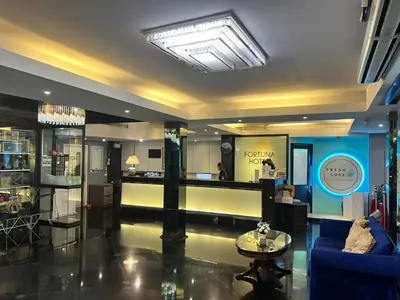 a living room with a blue couch and a table at Fortuna Hotel in Bangkok