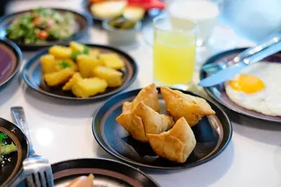 a table with plates of food and a glass of orange juice at Aspira Skyy Sukhumvit 1 in Bangkok