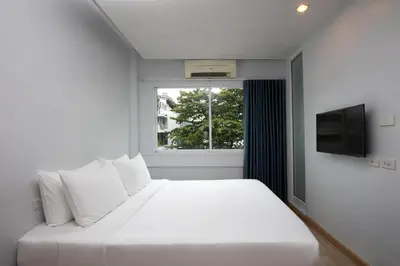 a white bedroom with a white bed and a window at Nantra Silom in Bangkok