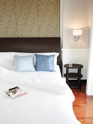 a bedroom with a white bed with blue pillows at Aurum The River Place in Bangkok