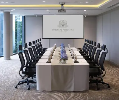 a conference room with a table and chairs and a screen at Oriental Residence Bangkok in Bangkok